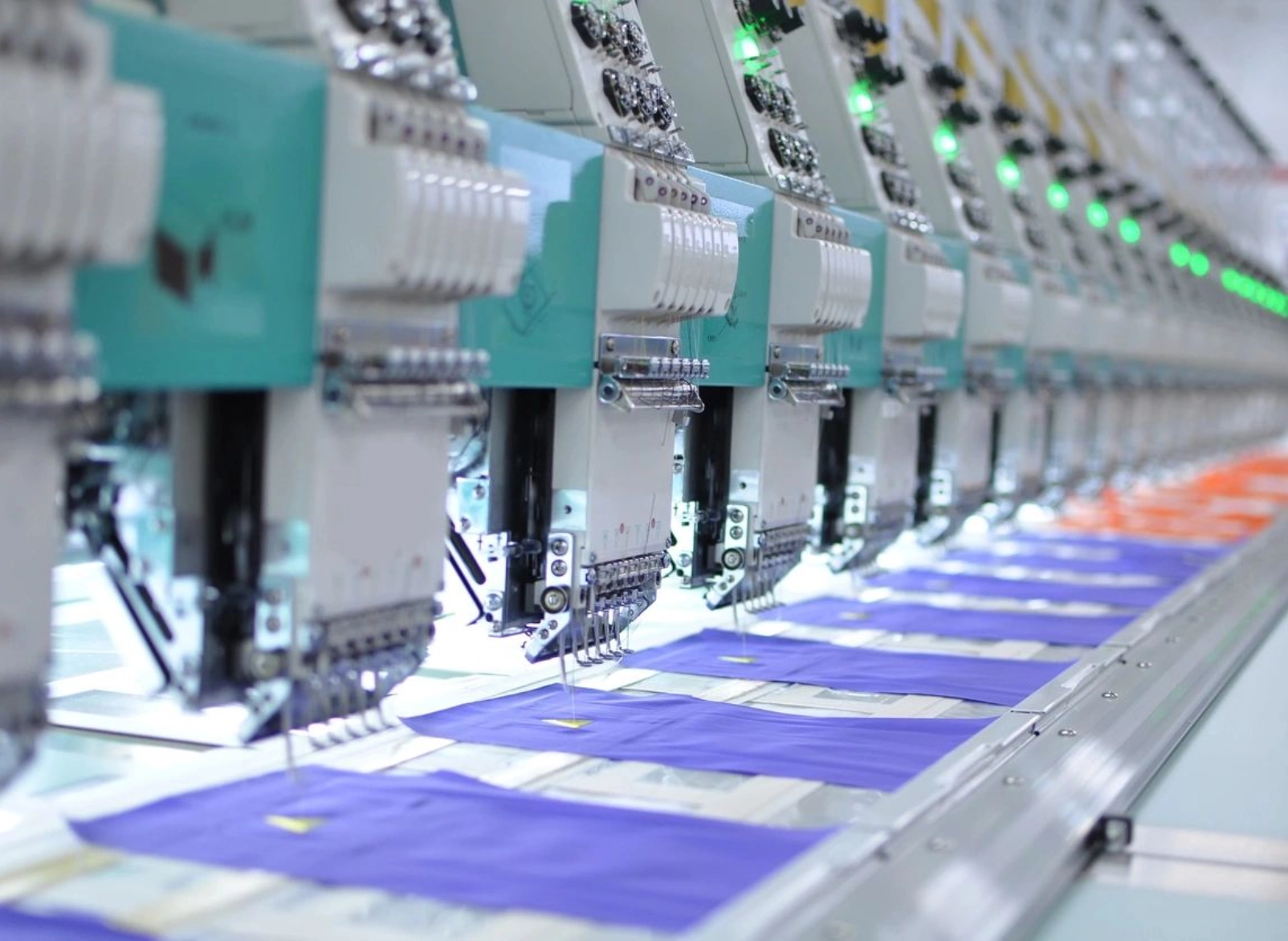 A row of machines in a factory with blue fabric on the floor.