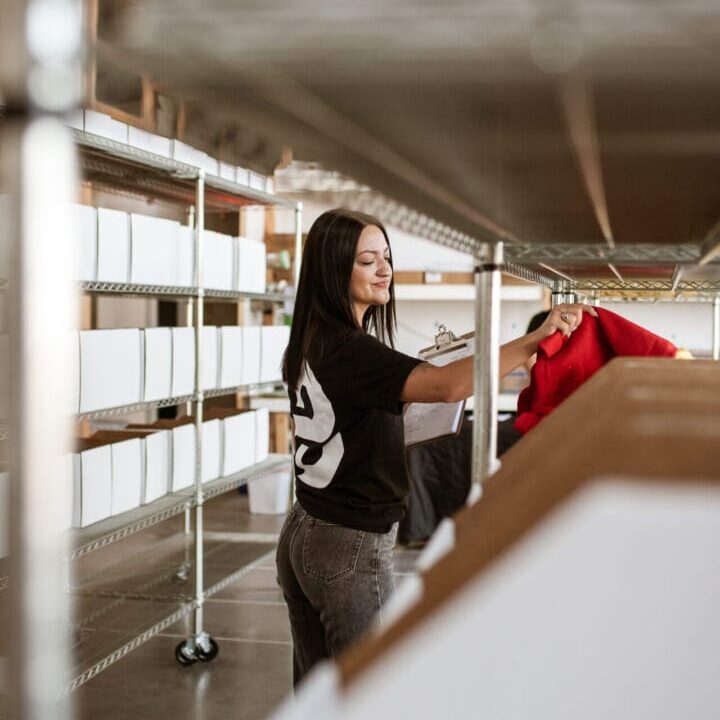 A woman standing in front of boxes on shelves.